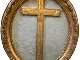 a wooden cross in a gold frame on the wall