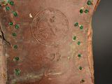 a close up of a brown vase with green stones on it