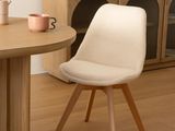 a white chair sitting in front of a table with a vase on it