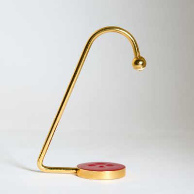 une lampe de bureau dorée sur laquelle se trouve un bouton rouge