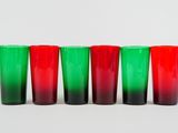 four red and green shot glasses lined up against a white background