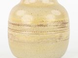 a yellow vase that is sitting on a white surface