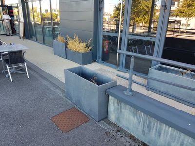 concrete planters on the side of a building next to a table and chairs
