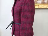 pink and black jacket on a mannequin stand in front of a painting