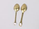 two spoons that are sitting on a white surface