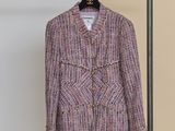 a pink jacket hanging on a clothes rack next to a white wall