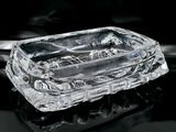 un cendrier en verre transparent posé sur une surface noire