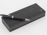 un stylo noir posé sur une boîte noire, à côté d'un stylo