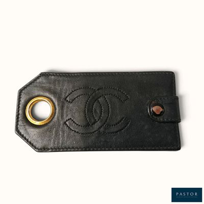 un gros plan sur une étiquette à bagages en cuir noir arborant le logo Chanel