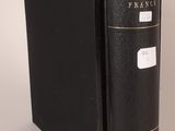 an old black book sitting on top of a table next to a white wall