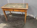 une vieille table en bois avec un plateau en verre, posée sur un sol en béton