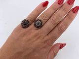 the woman ' s hand is holding a black and white ring
