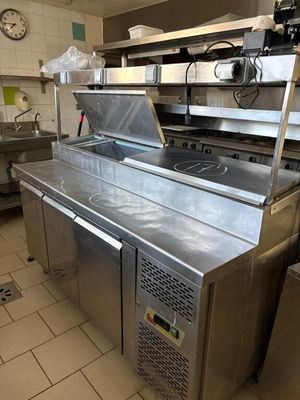 stainless steel counter top in a commercial kitchen with a clock on the wall