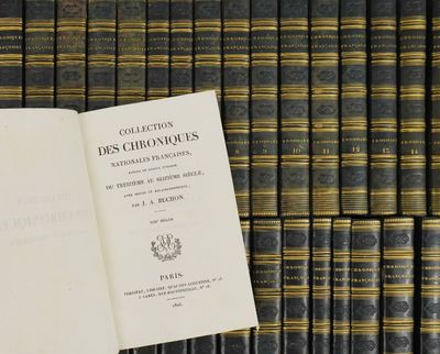 an open book sitting on top of a table in front of a bunch of books