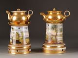 pair of gold and white vases with paintings on them on a table