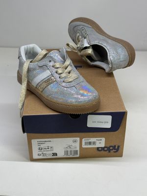 des chaussures de petit garçon dans une boîte posée sur une surface blanche