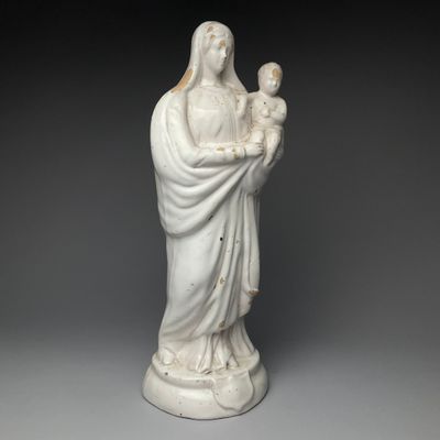 une statue blanche représentant une femme tenant un enfant dans ses bras