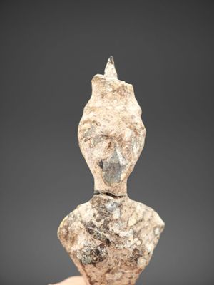 une main tenant une petite statue en pierre représentant une personne
