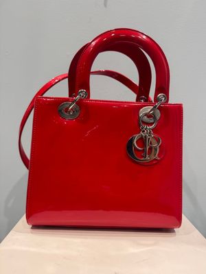 a red handbag with a silver logo on the handle
