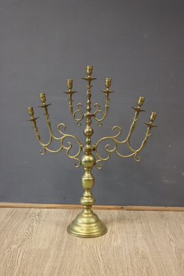un candélabre ancien en laiton à cinq bougies posé sur une table en bois