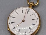 a gold pocket watch with roman numerals on it