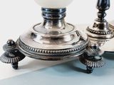 a silver candle holder with a white glass on top of it