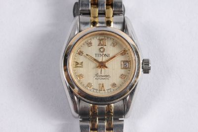 une montre-bracelet argentée et dorée posée sur une surface blanche