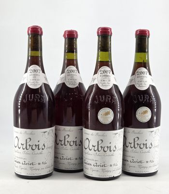 four bottles of wine are lined up on a white surface