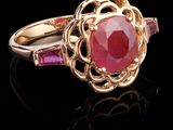 un gros plan d'une bague en or sertie d'une pierre rouge entourée de pierres roses