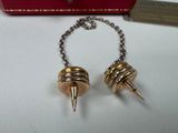 pair of gold spike earrings on a chain with a red box in the background