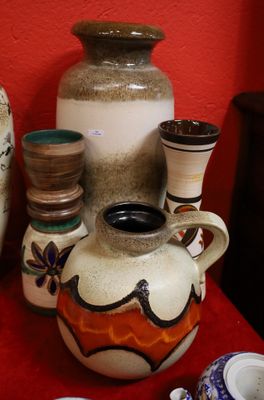 many different vases on a red table with a red wall in the background