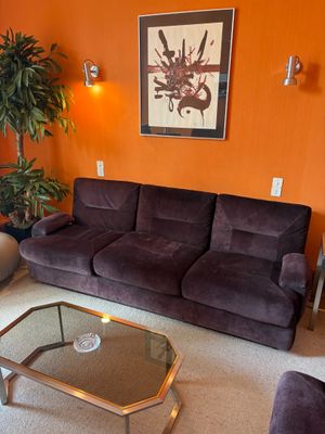 a living room with a couch, chair, coffee table and plant in it