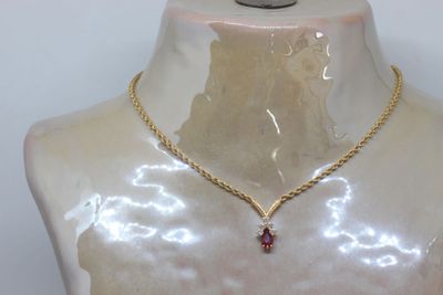gold chain necklace with a garnett on a mannequin torso