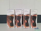 three boxes of knee braces sitting on a table in front of a wall