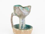une petite tasse avec une anse, posée sur une soucoupe