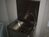 un lavabo en acier inoxydable avec un robinet, situé dans un coin de la salle de bains