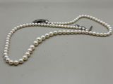 a close up of a white pearl necklace on a white surface