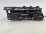 une vieille locomotive de jouet noire avec des roues rouges, posée sur une surface blanche