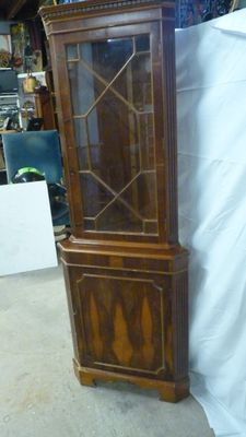 a tall wooden cabinet with a glass door on top of it