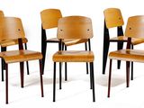 four wooden chairs are lined up against a white wall