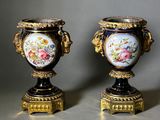 une paire de vases anciens décorés de fleurs peintes, posés sur une table