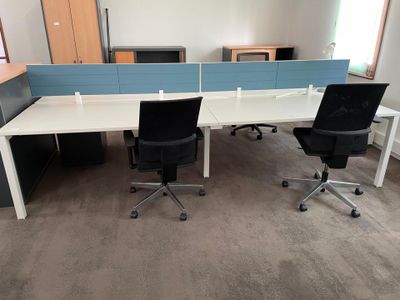 two desks with chairs in an office with a blue divider