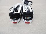 a pair of black and white vans shoes on a bed
