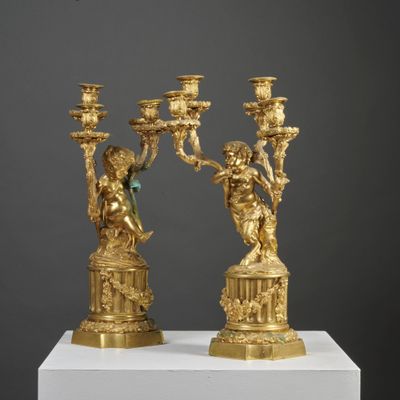 pair of gilded bronze candlesticks on pedestal on grey background