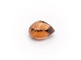 a close up of a faceted orange sapphire stone on a white surface