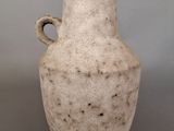 a white vase with a handle sitting on a table