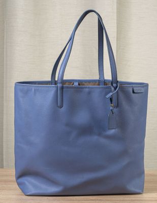 un sac fourre-tout bleu posé sur une table en bois