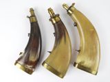 trois cornes ornées de ferrures en laiton sur fond blanc