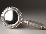 a silver magnifying glass with a handle on a table