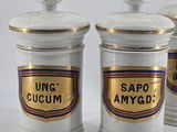 three white and gold canisters sitting on top of a white table